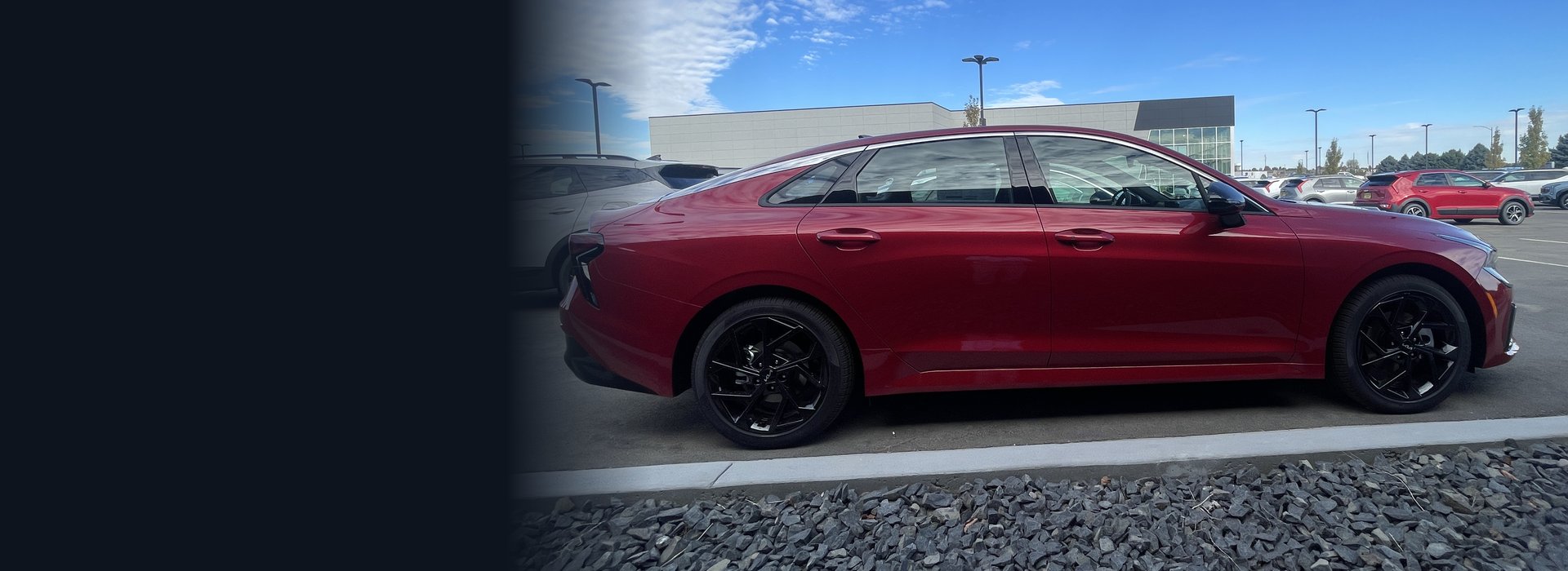 Red sedan parked on the lot at Overturf KIA in Pasco under a blue sky
